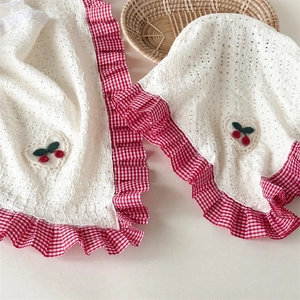 Close-up of baby bonnet and bib with cherry embroidery and gingham ruffle details