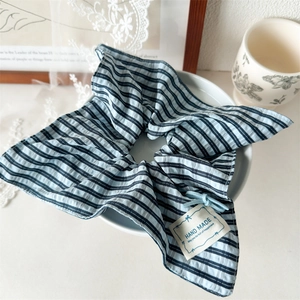 Detail of blue striped fabric scrunchie with Hand Made woven label in ceramic tray