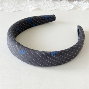 Detailed macro view of the padded fabric headband with blue bow print and diagonal stripes