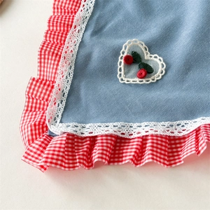 Detail of denim blue fabric with cherry embroidery and white lace trim edge