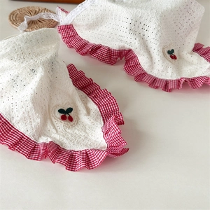 Close-up of pastoral lace-edged headscarf with cherry embroidery and red gingham trim