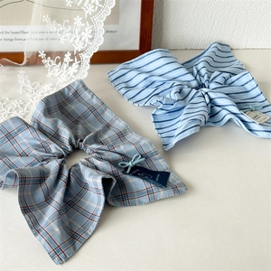 Detail of light blue plaid and striped fabric scrunchies with brand labels on lace fabric