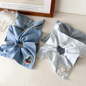 Gros plan détaillé sur des chouchous bleus en denim avec broderie de cœur en dentelle