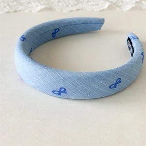Detailed texture of thick blue fabric headband with mini bows and handmade label