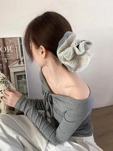 Detail of pleated organza scrunchie in light blue and grey mesh on low bun hairstyle