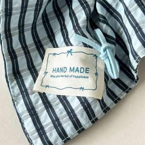 Close-up of handmade label on blue plaid fabric scrunchie with soft suede cord