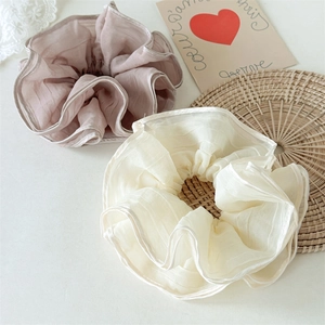 Detail view of pink and beige layered mesh scrunchies with elegant ruffled edges and textures