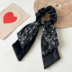 Detail of a floral black double-layered hair scrunchie with long ribbons and satin texture