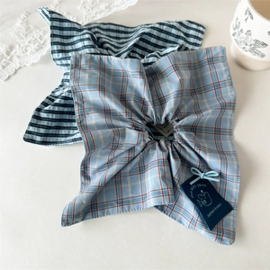 Detail of blue plaid fabric scrunchie with a decorative navy tag and teddy bear motif