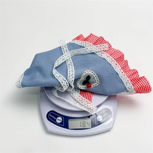 Detail shot of denim blue pet bandana with cherry patch on scale weighing 18.4g