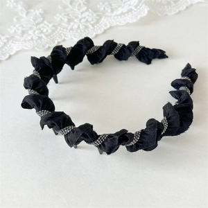 Close-up of black twisted fabric headband with pearlescent beads and non-slip teeth detail