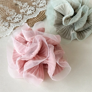 Detail of elegant organza scrunchies in pink and green with ruffled floral texture