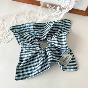 Detailed macro view of the blue and white striped scrunchie with handmade tag