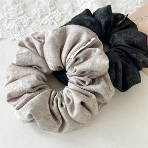 Detail of soft textured marble print scrunchies in beige and black fabric