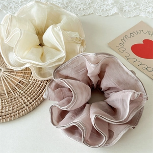 Close-up of layered mesh scrunchies in cream and dusty pink with elegant pleat textures