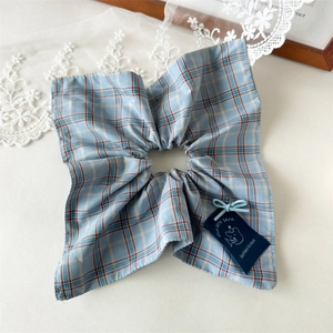 Detail of light blue plaid scrunchie with cute bear fabric tag on lace background