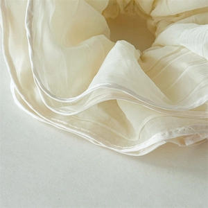 Close-up of beige pleated mesh fabric scrunchie with detailed white edge stitching