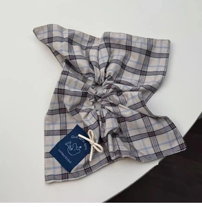 Detail view of plaid fabric scrunchie with cotton texture and blue brand tag