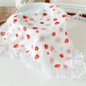 Close-up of white lace triangle scarf featuring red strawberry and cherry patterns