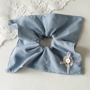 Détail d'un chouchou à carreaux bleus avec fleur en dentelle et bouton décoratif chic