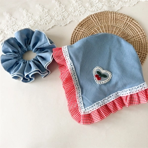 Detail of denim blue floral headscarf with cherry heart patch and red plaid ruffle trim