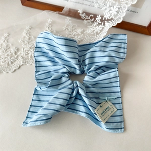 Close-up of light blue striped fabric scrunchie with a handmade label and wooden frame