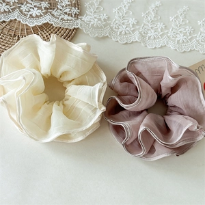 Detail of cream and dusty pink layered mesh scrunchies with pleated texture on a table