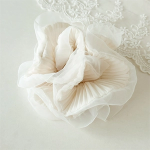 Detail of elegant ivory organza scrunchie with layered pleated edges and soft texture