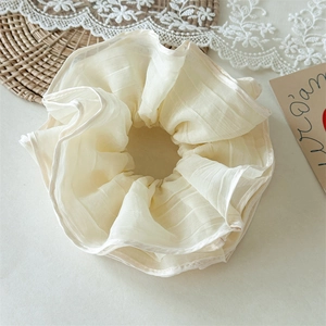 Close-up of oversized cream mesh scrunchie with soft pleated texture and organza fabric