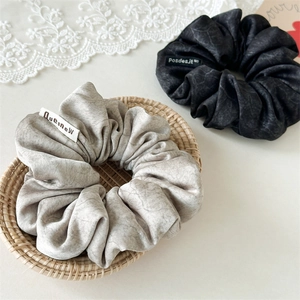 Detail of marble texture velvet scrunchies in grey and black with woven labels