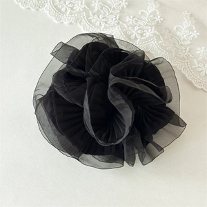 Detail of elegant black pleated organza hair scrunchie with a floral-like ruff design