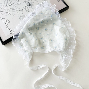 Detail of baby lace bonnet with blue cherry embroidery and delicate mesh ruffled trim