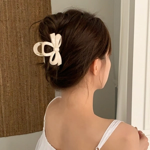 Détail d'une pince à cheveux en forme de nœud crème portée par un mannequin pour un chignon