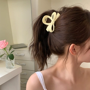 Détail de la pince à cheveux géante beige en forme de nœud pour un style queue de cheval