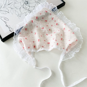 Close-up of pink checkered baby bonnet with red cherry prints and white lace ties