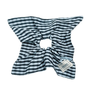 Blue striped fabric scrunchie with handmade tag and elegant pleats on white background