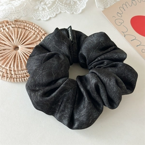 Detail of grey marble texture oversized scrunchie with soft fabric and branded woven label