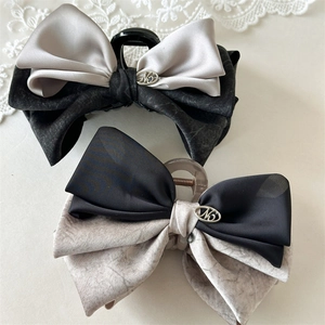 Detail of elegant padded bow hair claw clips with satin finish and metal logo accents
