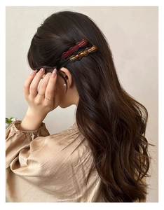 Dettaglio di fermagli per capelli ondulati in acetato rosso vino e tartarugati