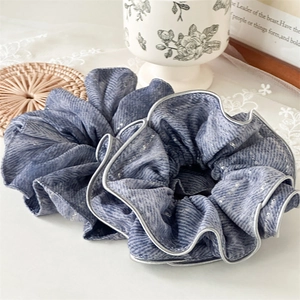 Detail of blue-grey ruffled hair scrunchies with silver glitter and textured fabric finish