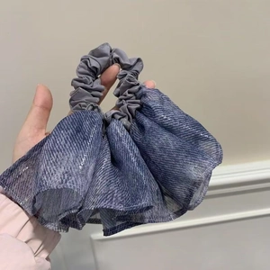 Detail view of a large grey-blue ruffled hair scrunchie with subtle silver glitter sparkles
