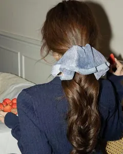 Detail of blue denim fabric scrunchie with layered ruffle bow shown on back of head