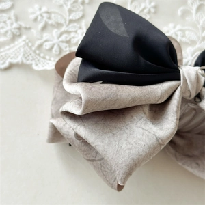 Detailed macro view of large marble and black fabric bow hair claw clip for women