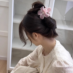 Détail d'une pince à cheveux fleur rose sur les cheveux sombres du modèle en chignon