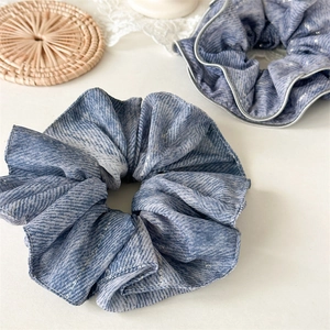 Close-up of elegant blue denim scrunchies with metallic threads and silver stitched edges