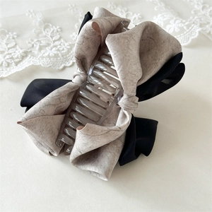 Detail of the large knotted bow hair claw clip with mixed gray and black fabric textures