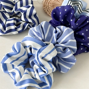 Gros plan de chouchous en soie à rayures bleues et motifs d'étoiles sur fond blanc