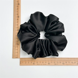 Grand chouchou en satin noir mesuré avec une règle en bois de 16 cm de diamètre
