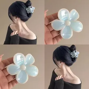 Détail d'une pince à cheveux fleur bleue en résine brillante avec perle centrale
