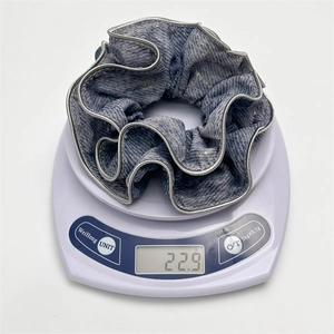 Detail view of a large blue textured scrunchie showing silver trim and weighing 22.9 grams